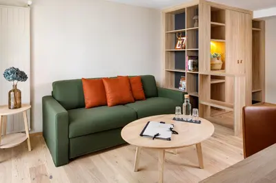a living room with a green couch and a table at Hotel Hirschen Wildhaus in Wildhaus