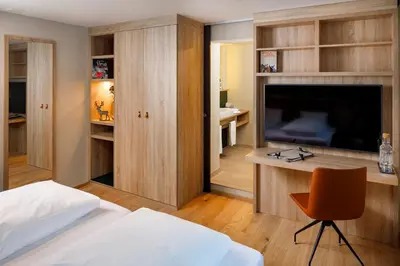 a bedroom with a bed and a desk with a television at Hotel Hirschen Wildhaus in Wildhaus