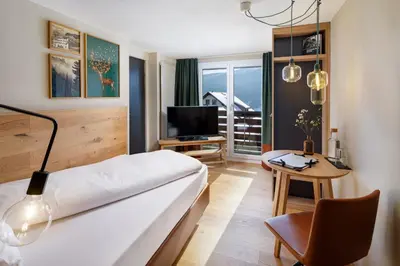 a hotel room with a bed and a table and a chair at Hotel Hirschen Wildhaus in Wildhaus