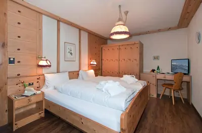 a bedroom with a large bed and a desk at Hotel Sonne in Wildhaus