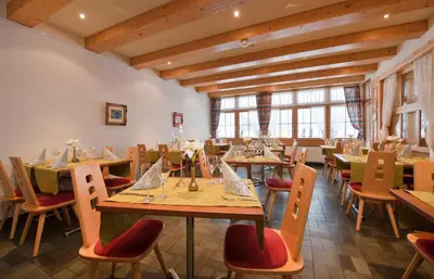 a restaurant with wooden tables and chairs and windows at Hotel Sonne in Wildhaus