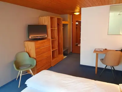 a bedroom with a bed and a tv and a desk at Adler Hotel in Appenzell