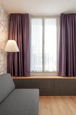 a living room with a window with purple curtains at Linde Heiden Swiss Quality Hotel in Heiden