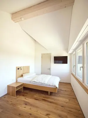 a bedroom with a bed and a tv on the wall at Hotel Rössli Tufertschwil in Lütisburg