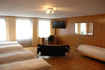 a hotel room with three beds and a television at Hotel Weisses Kreuz in St. Gallen