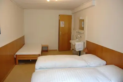 a room with two beds and a sink in it at Hotel Weisses Kreuz in St. Gallen