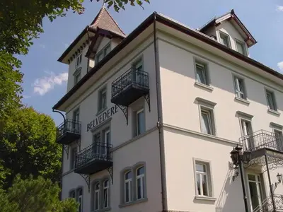 a large white building with balconies on top of it at Hotel Restaurant Belvedere in Weissbad