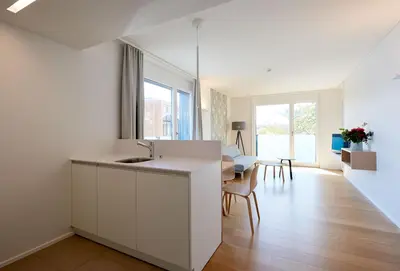 a white kitchen with a sink and a table at APPADU Appartements in St. Gallen