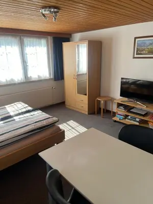 a living room with a table and a door and a tv at Ferienwohnung Inauen in Appenzell