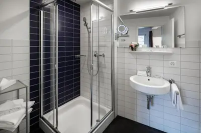 a bathroom with a glass shower and a sink at Hotel Le Lion - Self Check-in in Bischofszell