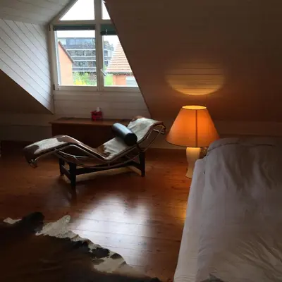 a bedroom with a bed and a chair and a lamp at Ruheges Zimmer, 100 m zum See, Strandbad in Bottighofen