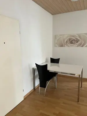 a white room with a table and two chairs at room service Joppich in St. Gallen