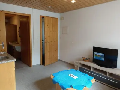 a living room with a table and a flat screen tv at Gasthaus Schäfli in Alt Sankt Johann