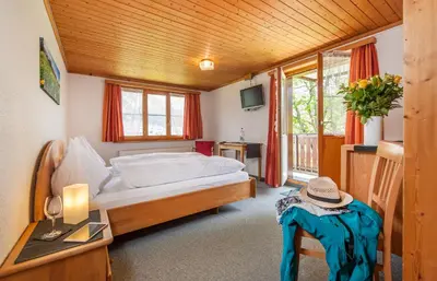 a bedroom with a bed and a desk andwindows at Schwendi Lodge in Unterwasser