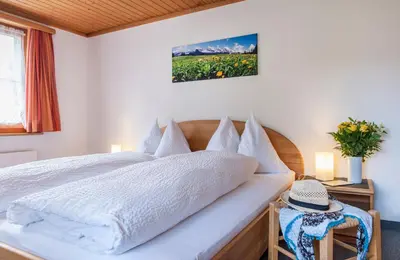 a bedroom with a bed with white sheets and flowers at Schwendi Lodge in Unterwasser