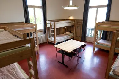 a dorm room with bunk beds and a table and chairs at Kreuzlingen Youth Hostel in Kreuzlingen