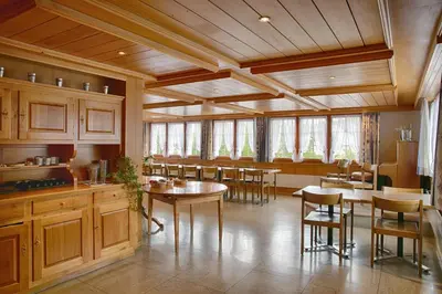 a large kitchen with wooden cabinets and tables and chairs at Loosmühle in Weissbad