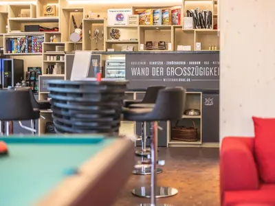 a room with a counter with chairs and a table at Lodge Hof Weissbad in Weissbad