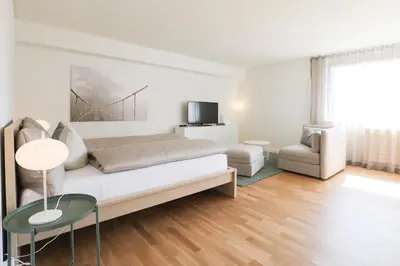 a white living room with a couch and a chair at Uze Apartments in Uzwil SG in Uzwil