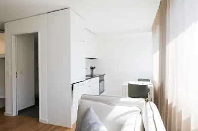 a white living room with a white chair and a table at Uze Apartments in Uzwil SG in Uzwil