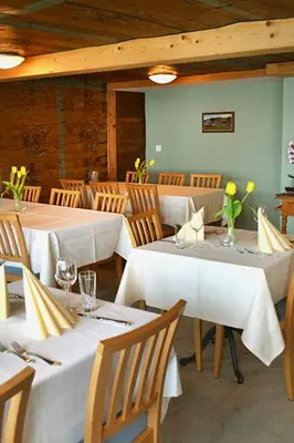 a restaurant with white tables and chairs with flowers on them at Gasthaus Löwen in Hemberg