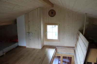a room with a bed and a clock on the wall at Chalet Nueschwendi in Ebnat