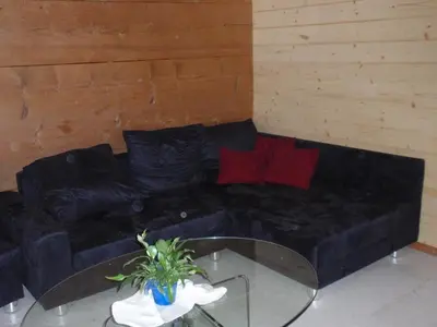 a black couch with red pillows and a glass table at Ferienwohnung Brülisauer in Brülisau