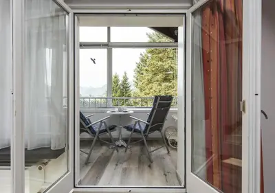 a sliding glass door leading to a balcony with a table and chairs at Bella Vista in Wildhaus