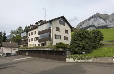 a large white building in front of a mountain at Bella Vista in Wildhaus