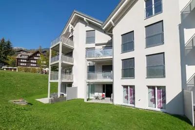 an exterior view of a white building with a green yard at Sunnewies in Wildhaus
