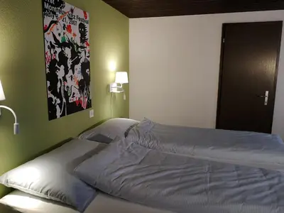 a large bed in a bedroom with a painting on the wall at Gasthaus Friedegg in Wildhaus