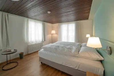 a bedroom with a bed with a wooden ceiling and two windows at Gasthaus Friedegg in Wildhaus