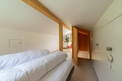 a bedroom with two beds and a door to a room at Steinrüti in Wildhaus