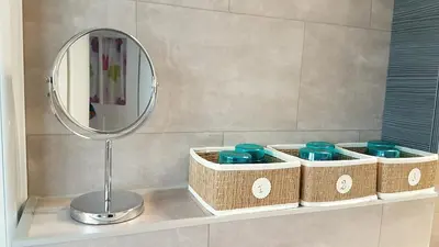 a mirror and baskets on a shelf in a bathroom at Family Mountain View - Upper Alley in Buchs