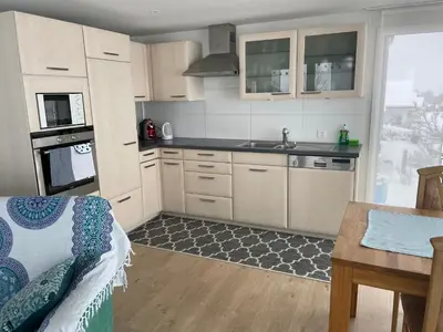 a kitchen with white cabinets and a sink and a table at Hälmli in Heiden