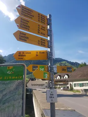 a street sign with many signs on a pole at Ferien im Gugger in Nesslau
