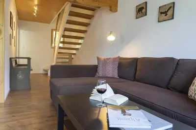 a living room with a couch and a table with a glass of wine at Schönau in Wildhaus