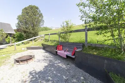 a bench with two red pillows on it next to a fence at Schönau in Wildhaus