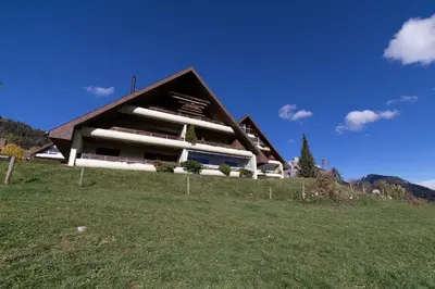 a building on top of a hill with a green field at Haldenblick in Unterwasser