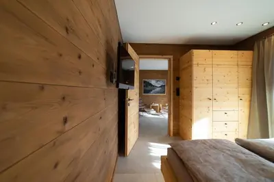 a bedroom with wooden walls and a hallway with two beds at Chalet Hinterrugg in Wildhaus