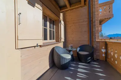 a patio with two chairs and a table on a deck at Chalet Gamserrugg in Wildhaus