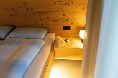 a small room with two beds in a wooden wall at Chalet Gamserrugg in Wildhaus
