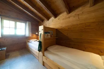 two beds in a wooden room with a window at Chalet Schafberg in Wildhaus