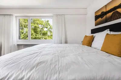 a white bedroom with a large bed and a window at SOHO 5B !Gratis Parken, Free Parking! in Kreuzlingen