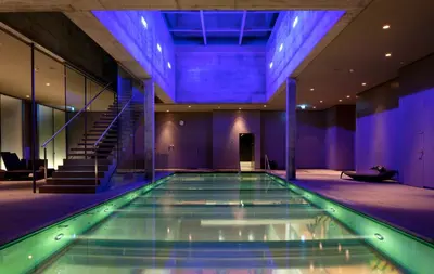 a swimming pool in a building with blue lighting at Einstein St. Gallen in St. Gallen