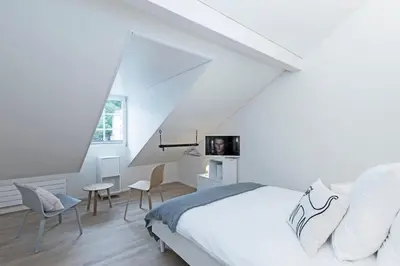 a white bedroom with a bed and chairs at Dom Studios in St. Gallen