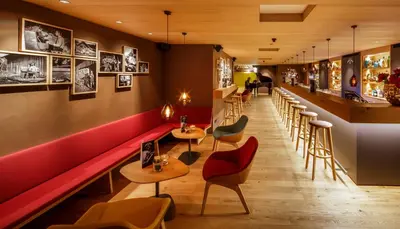 a restaurant with a red bench and tables and chairs at Hirschen Guesthouse - Village Hotel in Wildhaus