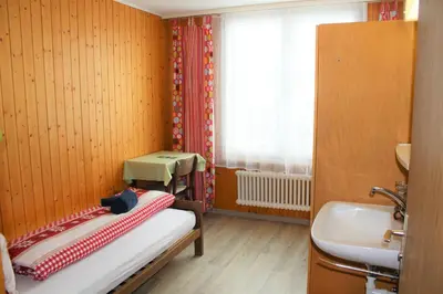 a small room with a bed and a sink at Galluszentrum in Wildhaus