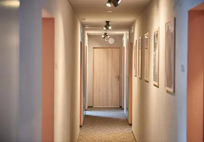 a hallway with orange walls and a door with pictures at Hotel Balga Natur- und Bikehotel in Balgach