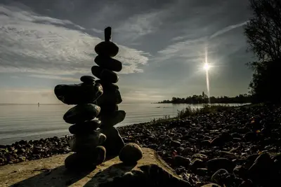 a stack of rocks sitting on a beach next to the water at Hotel Kreuzlingen am Hafen in Kreuzlingen